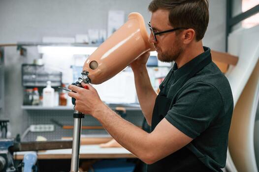 With prosthesis in ,hands. Technician working with prosthesis in modern laboratory photo
