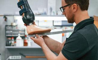 Standing, checking measure of the prosthesis. Technician working in modern laboratory photo