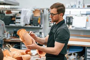 Using ,marker ,to draw the line. Technician working with prosthesis in modern laboratory photo