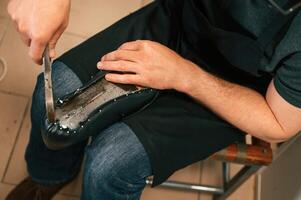 Working, with nails, on the shoe. Close up view of man that is sitting photo