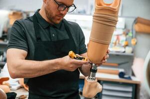 Tightening, the, screws. Technician working with prosthesis in modern laboratory photo