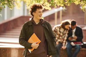 With ,yellow colored ,notepad. Young students in casual clothes are together outdoors photo