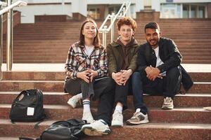 Looking at the camera... Young students in casual clothes are together outdoors photo