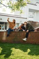 Tree with, green leaves. Four young students in casual clothes are together outdoors photo
