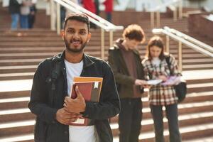 Stairs that, is, going up to university building. Young students in casual clothes are together outdoors photo