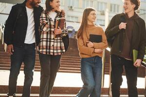 Front view. Four young ,students in casual clothes are together outdoors photo