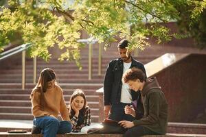 Hanging ,out after lessons. Four young students in casual clothes are together outdoors photo