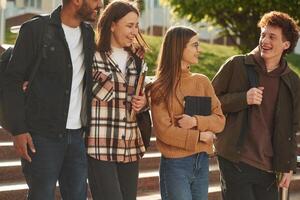 Front, view. Fou,r young ,students in casual clothes are together outdoors photo