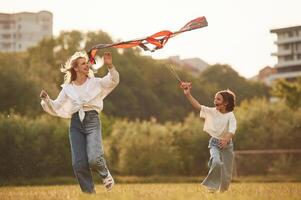 Playing with kite. Woman with her little daughter are on the summer field together photo