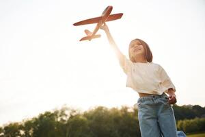 Front ,view. Happy ,little girl is playing with toy plane outdoors photo