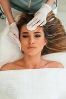 Cotton, pad or sponge are ,used to ,clean the skin. Woman face getting facial care by beautician hands at spa salon photo
