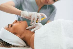 Syringe, for a rejuvenating ,injection. Woman face getting facial care by beautician hands at spa salon photo