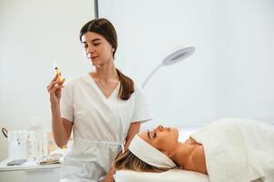 Syringe, for a rejuvenating injection. Woman face getting facial care by beautician hands at spa salon photo