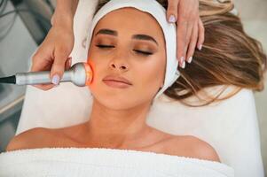 Apparatus, for galvanization is used. Woman face getting facial care by beautician hands at spa salon photo