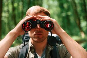 Looking through the binoculars. .Tourist, in summer forest. Conception of exploration and leisure photo