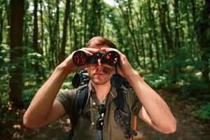 Looking, through ,the binoculars. Tourist in summer forest. Conception of exploration and leisure photo