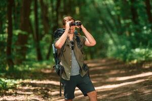 Looking ,through, the, binoculars. Tourist in summer forest. Conception of exploration and leisure photo