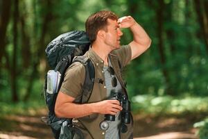 Navigation ,conception. With binoculars. Tourist in summer forest photo