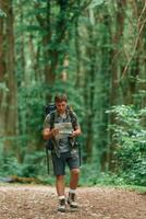 Walking forward with map in hands. Tourist in summer forest. Conception of exploration and leisure photo