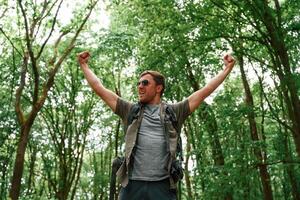 Enjoying the freedom, hands to the sides. Tourist in summer forest. Conception of exploration and leisure photo