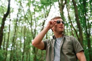 In sunglasses. Tourist, in summer forest. Conception of exploration and leisure photo