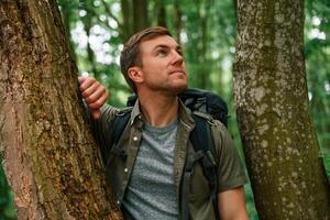 Standing,, between the trees. Tourist in summer forest. Conception of exploration and leisure photo