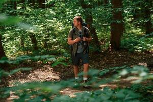 Looking ,for the way. Holding binoculars. Tourist in summer forest. Conception of exploration and leisure photo