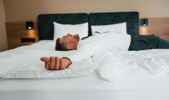 Tired, lying down ,on ,the bed. Businessman is indoors in the hotel room photo