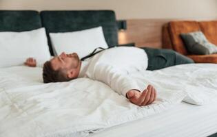 Tired, lying down on the bed. Businessman, is indoors in the hotel room photo