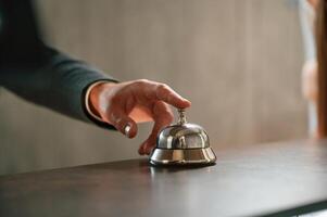 Close up view, using hotel desk bell.. A man in a black jacket at the hotel reception photo