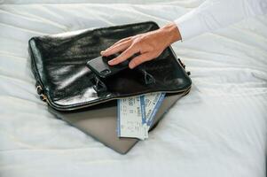 Close up view, of businessman that is sitting on bed with tickets for travel on it photo