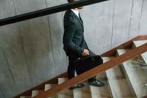 Walking up. Man in business, suit ,and tie with case in hands is on the stairs photo