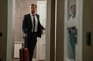 Entering ,the appartment and and holds a suitcase in his hands. Handsome businessman is indoors in the hotel room photo