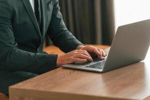 Close up view of businessman in suit and tie that is working by using laptop photo