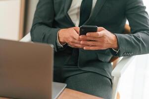 Close ,,up view of businessman that is sitting and using smartphone photo