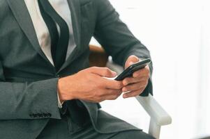 Close up view ,of businessman that is sitting and using smartphone photo