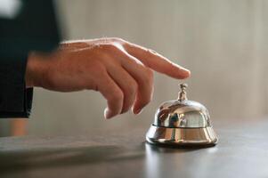 Close ,up view, using hotel desk bell. A man in a black jacket at the hotel reception photo