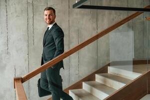 With case in hands.. Man in business suit and tie is on the stairs photo