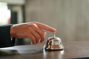 Close up view, using ,hotel desk bell. A man in a black jacket at the hotel reception photo