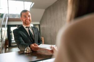 Woman ,serves ,a visitor.. A man in a black jacket at the hotel reception photo