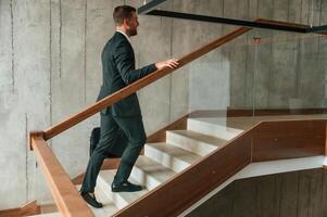 With ,case, in hands. Man in business suit and tie is on the stairs photo