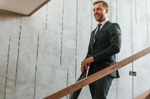 Man in ,business suit and tie with case in hands is on the stairs photo