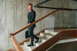 With ,case in hands. Man in business suit and tie is on the stairs photo