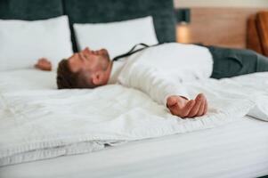 Tired,, lying down on the bed. Businessman is indoors in the hotel room photo