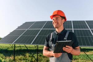 Summer time, standing and holding ,digita,l tablet. Man is doing operating and maintenance in solar power plant photo