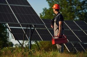 Red repair toolbox is in hands. ,Man, is doing operating and maintenance in solar power plant photo