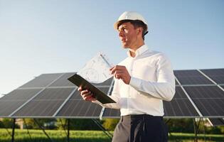 Notepad with document is in hands. Man is doing operating and maintenance in solar power plant photo