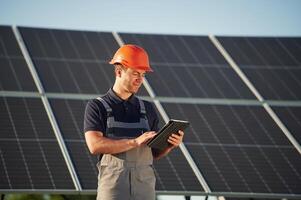Tablet ,in, hands. Man is doing operating and maintenance in solar power plant photo