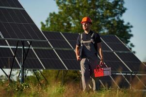 Red r,epair toolbox is in hands. Man ,is doing operating and maintenance in solar power plant photo
