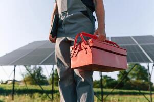Walking and holding repair toolbox. Close up view of man that is doing maintenance in solar power plant photo